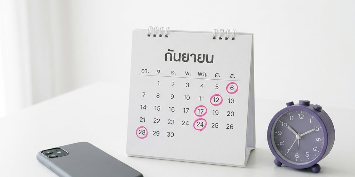 ปฏิทินตั้งโต๊ะที่วงวันที่ด้วยปากกาสีชมพู ข้างมือถือและนาฬิกาปลุกสีม่วงบนโต๊ะสีขาว